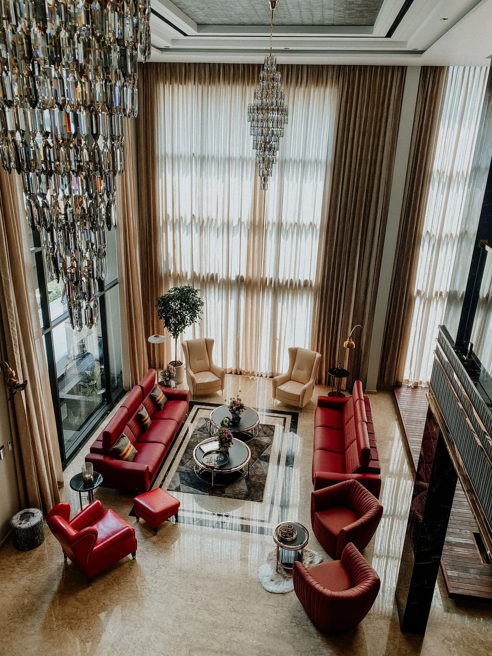 Rich living room with deep red sofas, tall curtains and a crystal chandelier